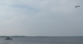 Helicopter flying over a boat on water.
