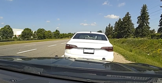 White sedan ahead on a highway, clear sky