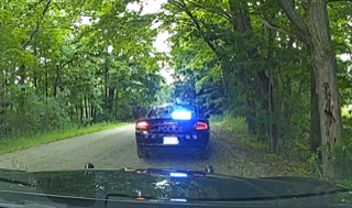 Police car with flashing lights on a rural road.