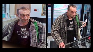 Man wearing a black t-shirt that reads &quot;ONE MORE SNOOZE&quot; and a plaid shirt, looking directly at the camera