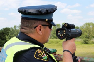 Man in police uniform holding a device.