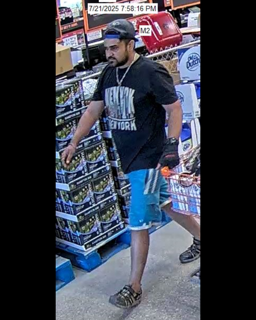 Man wearing a black t-shirt that says &quot;New York&quot; and blue denim shorts.