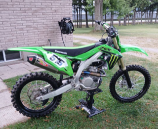 Green Kawasaki dirt bike on a stand.