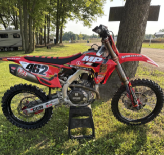 Red dirt bike with black and red graphics, number 462, standing on a black stand