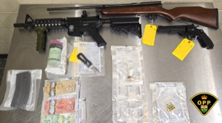 Two rifles, bundles of Canadian currency, and packages of drugs.