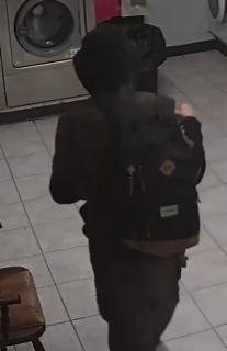 Person wearing a black hoodie and backpack, seen from behind.