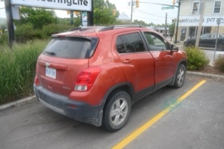 Red Chevrolet Trax parked next to a curb.