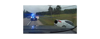 Damaged white car on roadside, police lights visible
