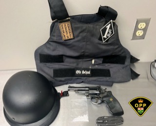 Black helmet, body armor, handgun, and a police patch
