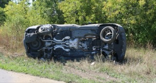 Black car overturned in tall grass