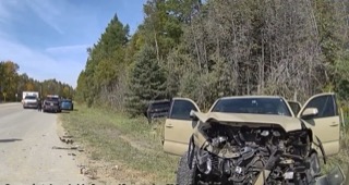 Damaged beige truck on the shoulder of a road, with police vehicles nearby.