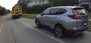 Silver SUV with rear damage, school bus in the distance