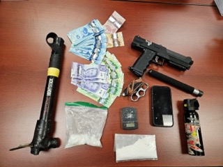 Pile of Canadian currency, a handgun, a taser, and small baggies.