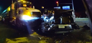Damaged black car and semi-truck at night