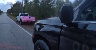 Pink pickup truck on a rural road.