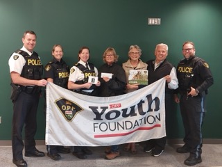 Six people holding a banner that reads &quot;OPP Youth Foundation.&quot;