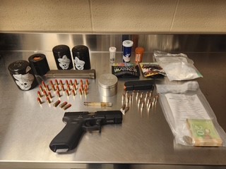 Black handgun, ammunition, and baggies on a metal surface