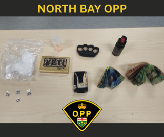 White powder in baggie, lighter, brass knuckles, baggie with pills, banded Canadian money
