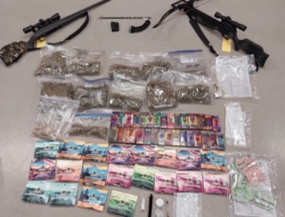 Two rifles, numerous bags of a leafy substance, stacks of cash, and paperwork.