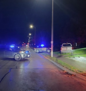 Police vehicles with flashing blue and red lights at a nighttime accident scene.