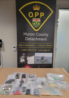 Ontario Provincial Police sign, Huron County Detachment, Safe Communities, A Secure Ontario, 1-888-310-1122, www.opp.ca, several small baggies containing white powder and other substances on a table