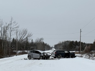 Two cars collided, covered in snow.