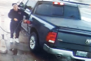 Black pickup truck being washed. Person in black hoodie and white pants washing the vehicle.