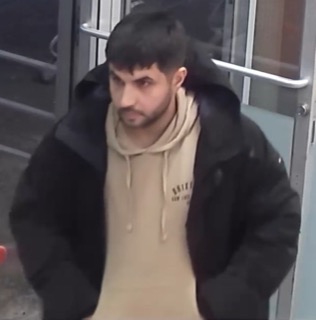 Man in a black jacket and beige hoodie
