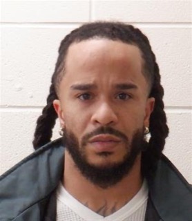 Man with locs and beard, looking directly at the camera