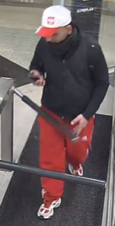Person in a black turtleneck, red tracksuit pants, and a white baseball cap