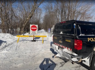 Road closed sign, yellow barricade, police truck in snow