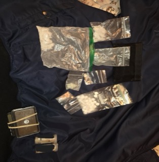 Small plastic bags of white powder, a hammer, and a small toolbox on a dark blue surface.