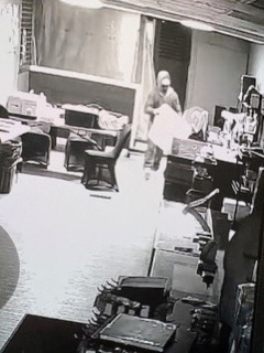 Person carrying a white object in a cluttered room