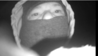 Person wearing a black face mask and a white hoodie.