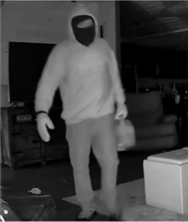 Person in a hooded sweatshirt and pants, holding a bag.