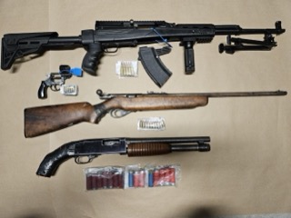 Three firearms and ammunition on a surface.