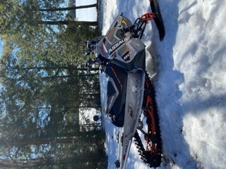 Polaris snowmobile, black and orange, on snow