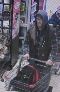 Person in a shopping cart, wearing a hat and jacket
