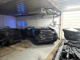 Several cars covered in plastic sheeting.