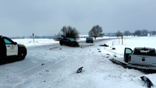Damaged vehicles on a snowy road, police vehicle present