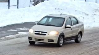 Silver Chevrolet Aveo driving on snow-covered road