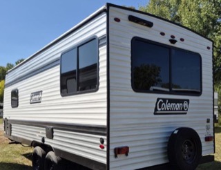 White RV with black wheels and red accents. Coleman logo.