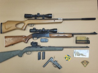 Air rifle with scope, ammunition, and accessories on a yellow surface.