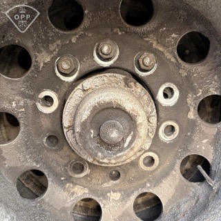 Close-up of a truck wheel hub with visible lug nuts and a corroded center.