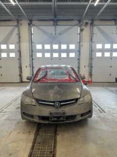Silver Acura with plastic wrap covering the front bumper