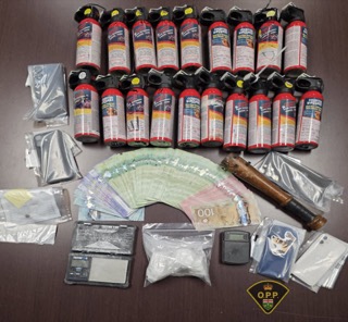 Stacks of pepper spray, Canadian currency, digital scales, and plastic baggies.
