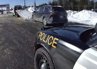 Police vehicle, black and white, &quot;POLICE&quot; in yellow lettering. Snow-covered ground.