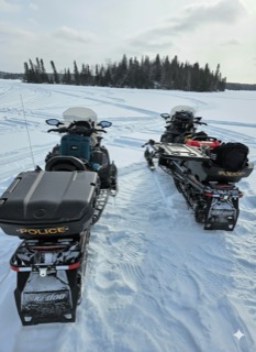 Two snowmobiles, both marked with &quot;POLICE,&quot; on a snow-covered landscape