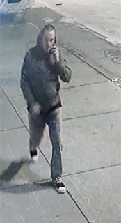 Person walking, wearing a hooded sweatshirt and jeans
