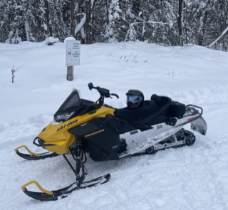 Yellow and black snowmobile in snow.